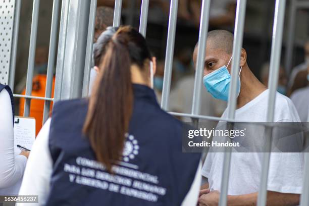 In this handout picture provided by the Salvadoran presidency A member of the humanitarian delegation speaks to inmates during a humanitarian visit...