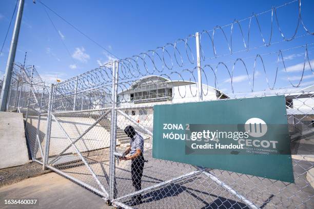 In this handout picture provided by the Salvadoran presidency A guard opens a gate before a humanitarian visit to counter-terrorism confinement...