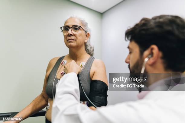 patient, der während eines kardiopulmonalen belastungstests in einem krankenhaus von einem arzt untersucht wird - belastungsprobe stock-fotos und bilder