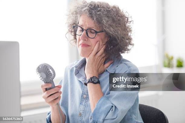menopausal femme avoir une bouffée de chaleur au bureau - éventail photos et images de collection
