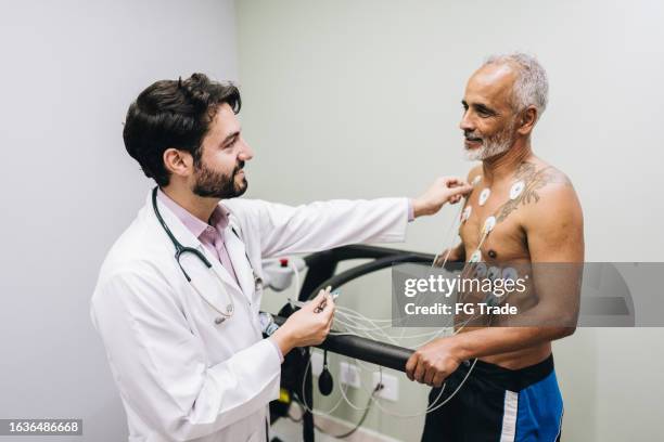 doctor talking with his patient while put sensors on her in a doctor's office - stress test stock pictures, royalty-free photos & images