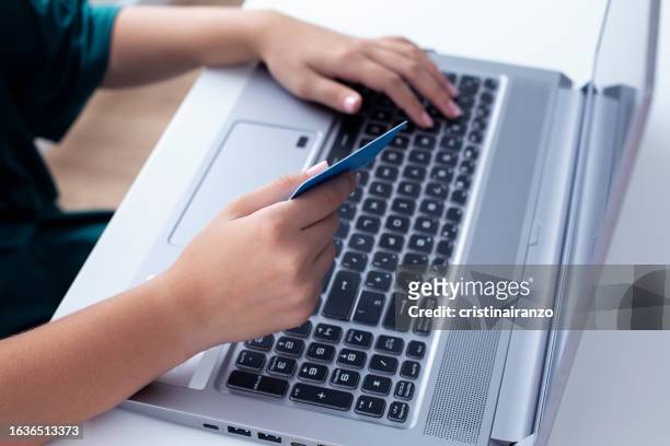 woman using laptop and holding credit card - cristinairanzo stock pictures, royalty-free photos & images