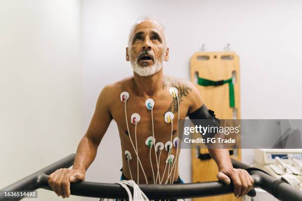 älterer patient, der in einer arztpraxis einen kardiopulmonalen belastungstest durchführt - belastungsprobe stock-fotos und bilder