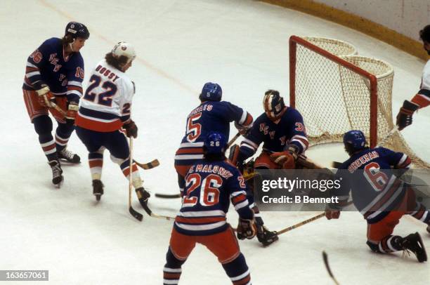 Mike Bossy of the New York Islanders goes for the puck against goalie John Davidson, Pat Hickey, Carol Vadnais, Dave Maloney and Bobby Sheehan of the...