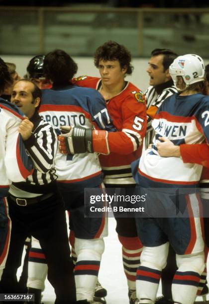 Phil Russell of the Chicago Blackhawks is held back by Phil Esposito of the New York Rangers as linseman John D'Amico holds back a Rangers player...