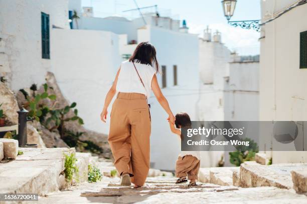 rear view of young asian mother and her little girl holding hands, walking in ostuni, puglia - brindisi stock pictures, royalty-free photos & images