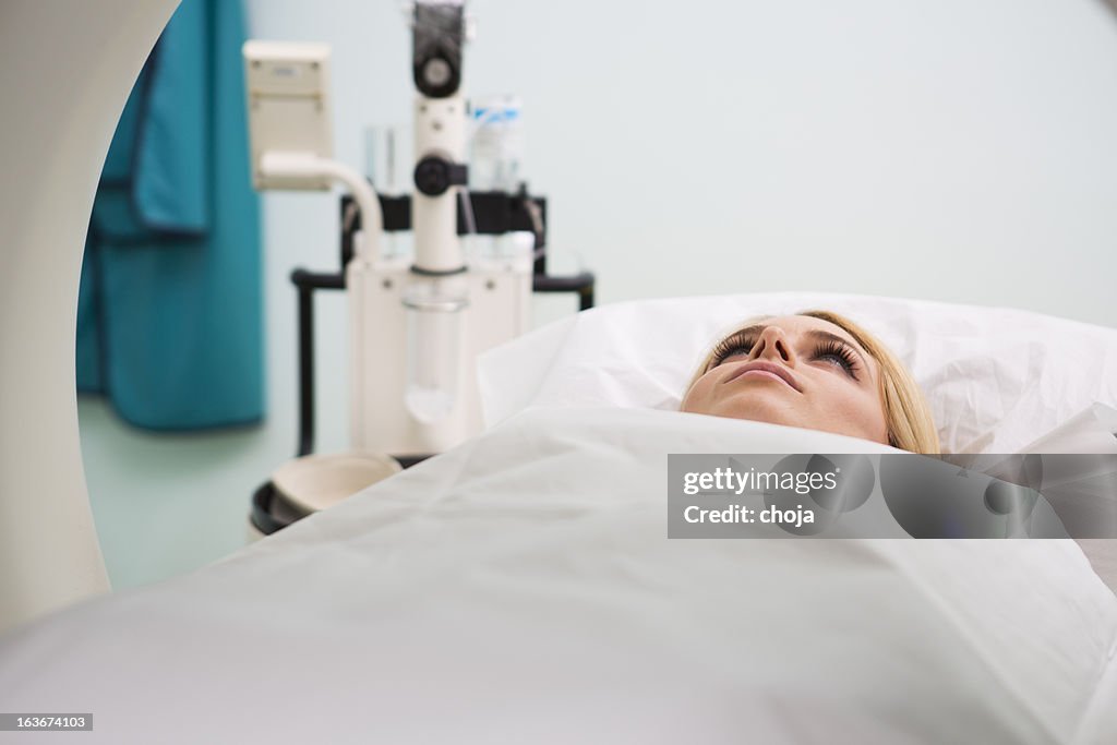 Young woman waiting for CAT scan with contrast
