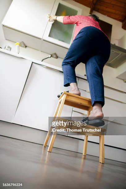 Symbolic photo on the topic of accident risk in the household. An old woman is standing on a stool in a kitchen on August 31, 2023 in Berlin, Germany.