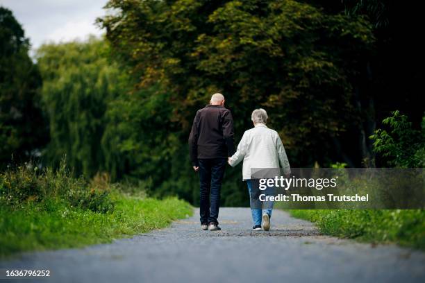 Symbolic photo on the subject of pensioners. An elderly couple walk hand in hand along a path together on August 30, 2023 in Berlin, Germany.