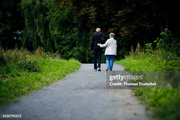 Symbolic photo on the subject of pensioners. An old married couple is walking along a path together, with the wife supporting her husband on August...