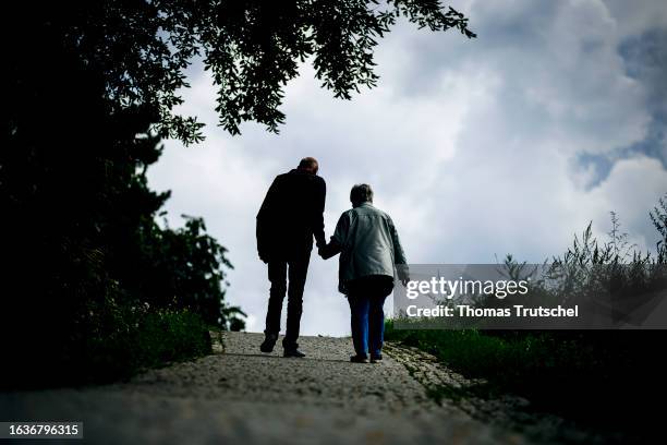 Symbolic photo on the subject of pensioners. An elderly couple walk hand in hand along a path together on August 30, 2023 in Berlin, Germany.