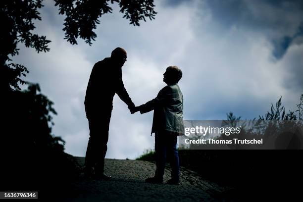 Symbolic photo on the subject of pensioners. An elderly couple walk hand in hand along a path together on August 30, 2023 in Berlin, Germany.