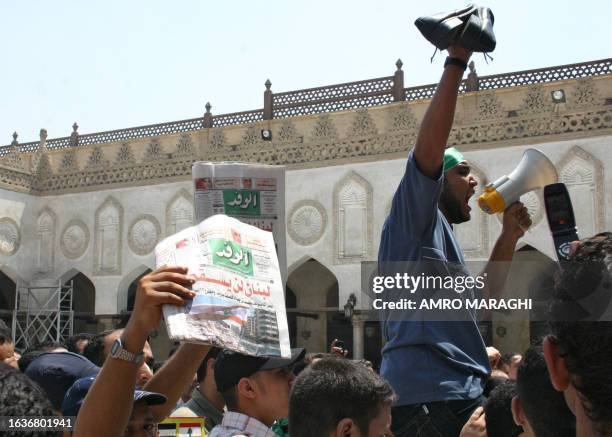 Egyptian Muslims, one of them holding copies of the local daily newspaper Al-Wafd with the front page title: 'Lebanon will not fall', protest against...