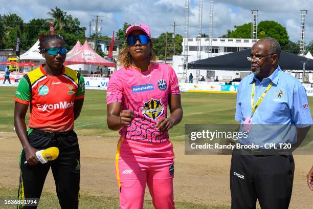 Hayley Matthews of Barbados Royals toss the coin as Stafanie Taylor of Guyana Amazon Warriors and match referee Stephen Proverbs look on during the...