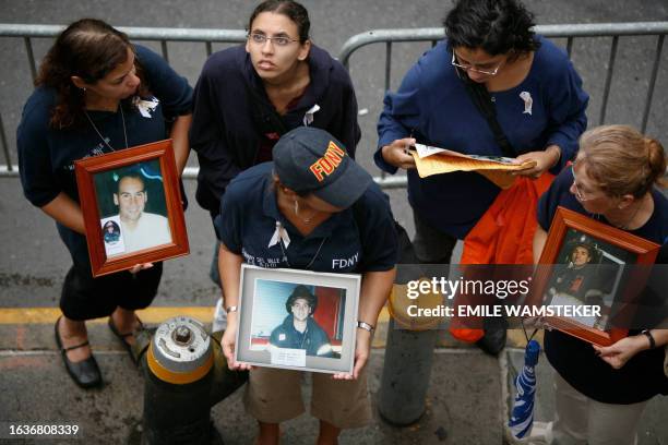 Group of women holding pictures of firefighters stand 11 September 2007 in front of Engine Co 10 outside the World Trade Center site during memorial...