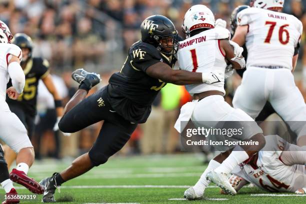 Zach Lohavichan of the Wake Forest Demon Deacons tackles Jalen Hampton of the Elon Phoenix during a football game at Allegacy Federal Credit Union...