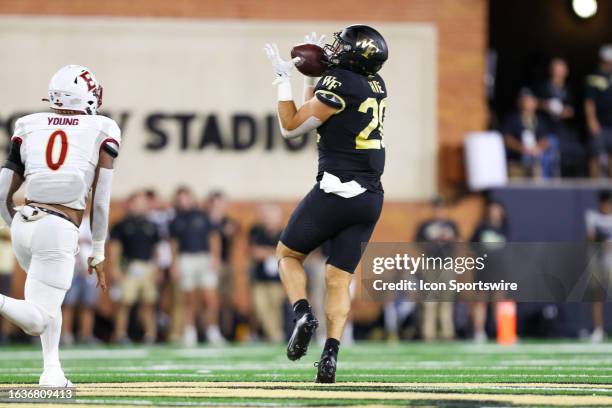 Cameron Hite of the Wake Forest Demon Deacons catches a pass during a football game as TJ Young of the Elon Phoenix attempts to chase him down at...