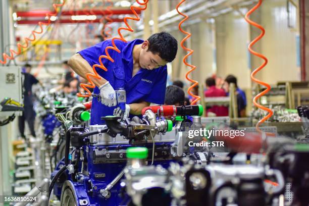 This photo taken on August 31, 2023 shows a worker assembling an engine at an engine manufacturing factory in Qingzhou, in China's eastern Shandong...