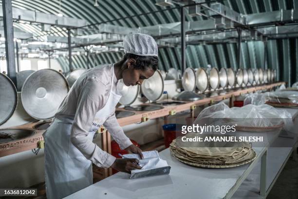 Woman counts fresh baked injera -traditional fermented flatbread- at Lemi Kura Injera Factory in Addis Ababa, Ethiopia on August 31, 2023.