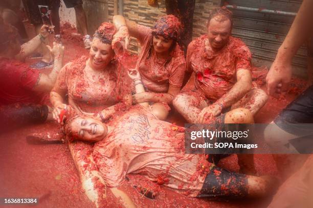 Group of tourists are covered with crushed tomatoes during the Tomatina festival. Every last Wednesday of August, La Tomatina is celebrated in the...