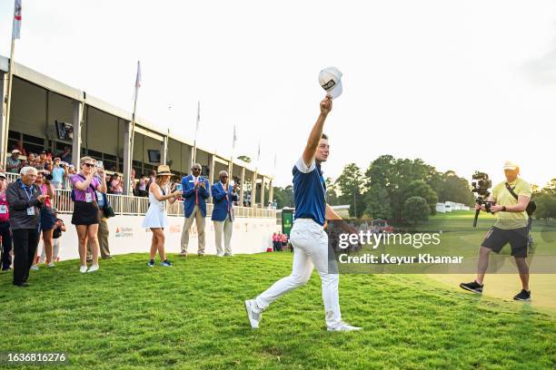 Viktor Hovland of Norway smiles and tips his hat to fans near a Vox Media Studios camera filming for the Netflix Full Swing series following his...
