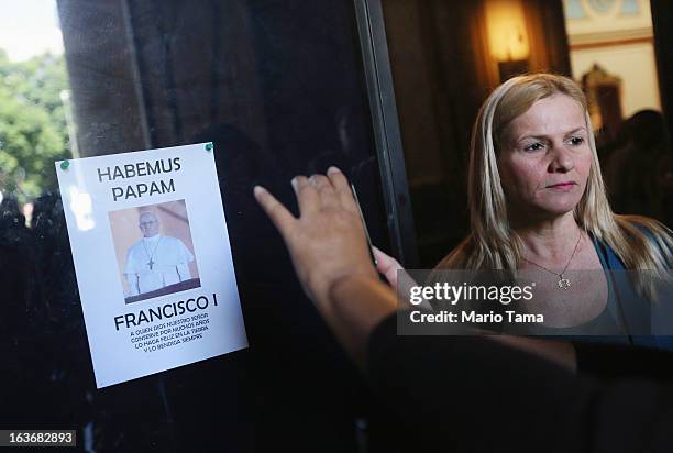 People take photos next to a picture of pope Francis in the entrance to the Metropolitan Cathedral after Mass on the day after Pope Francis was...