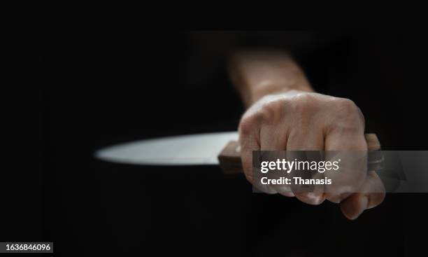 close-up of a person's hand brandishing a menacing knife - kitchen knife stock-fotos und bilder