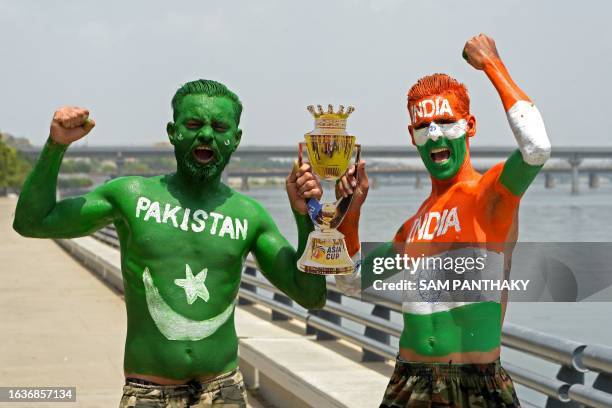 Fans with their bodies painted as national flags of India and Pakistan hold a cut-out of the Asia cup trophy in Ahmedabad on September 1 on the eve...