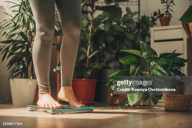 a young woman is weighing herself in a weighing scale - perte photos et images de collection