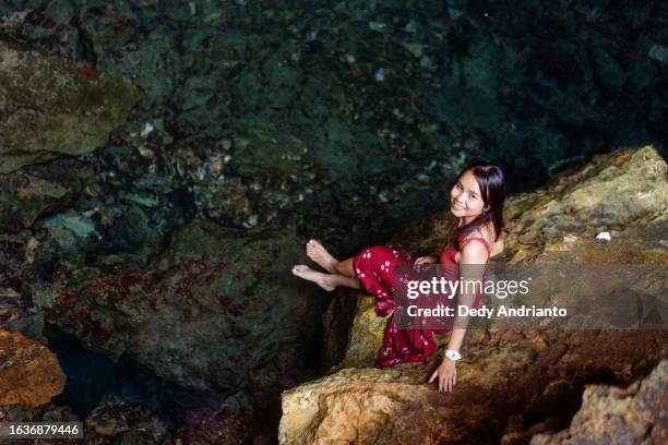 schöne asiatische frau sitzt in der goa balo-höhle auf der insel selayar - balonnen stock-fotos und bilder