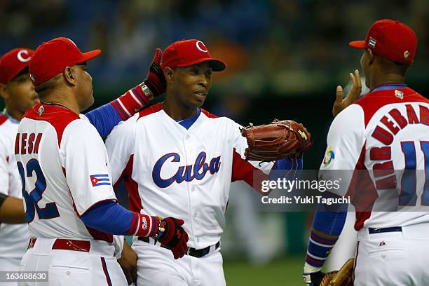 Danny Betancourt of Team Cuba is greeted by manager Victor Mesa in the dugout after the top of the sixth inning during Pool 1, Game 3 between the...