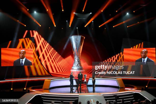 Cameroonian former football player Stephane Mbia arrives on stage with the UEFA Europa League Trophy during the draw ceremony for the group stages of...