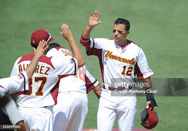 Martin Prado of Team Venezuela is greeted by teammates in the dugout after scoring a run in the bottom of the fourth inning during Pool C, Game 5...