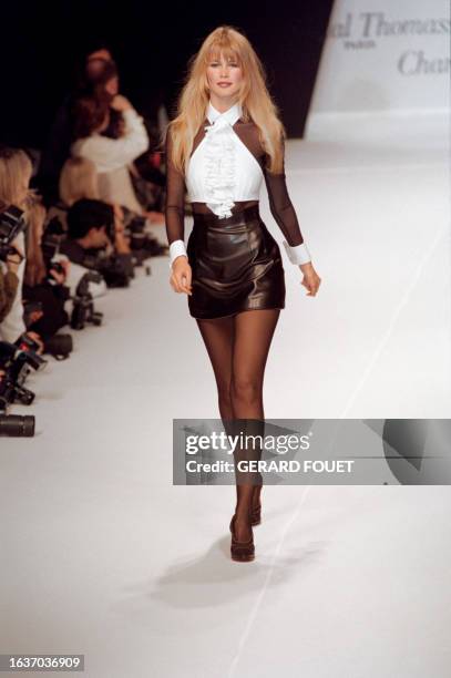 German model Claudia Schiffer presents this ruffled and sheer, black and white top over a very short black leather skirt during the Chantal Thomass...