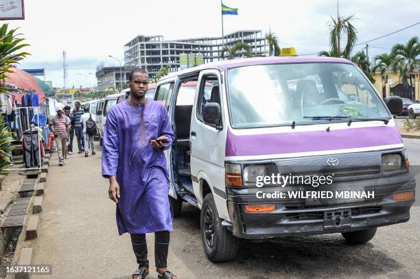 Man walks past a minibus taxi in Libreville on September 1, 2023. Gabon's new strongman General Brice Oligui Nguema has blasted corruption among...