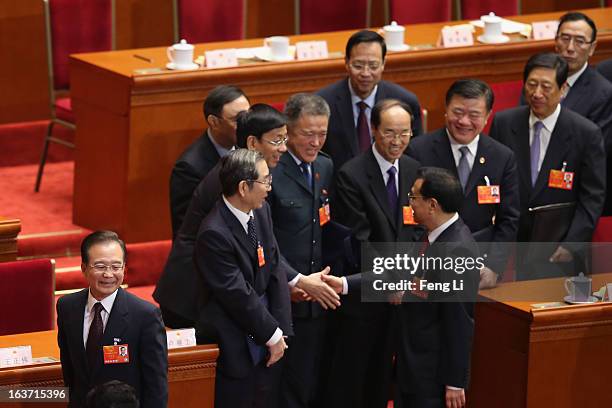 Central officials shake hands with China's newly-elected Premier Li Keqiang as former Premier Wen Jiabao leaving during the fifth plenary meeting of...