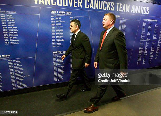 General manager Mike Gillis of the Vancouver Canucks and assistant general manager Laurence Gillman walk through the arena before an NHL game against...