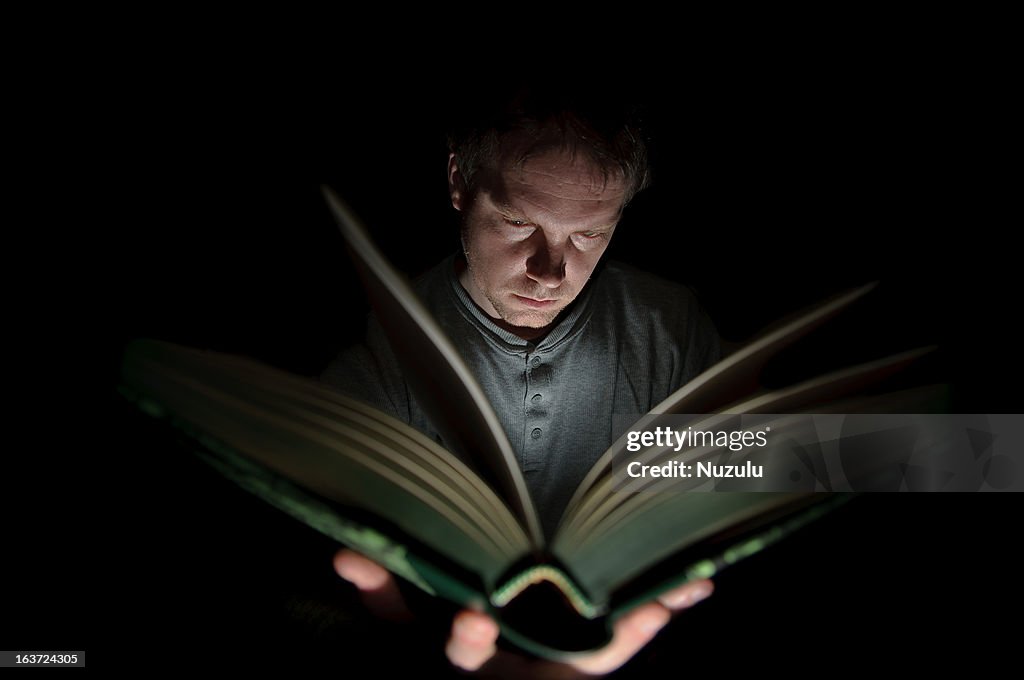 Man Reading Book Illuminated by Light