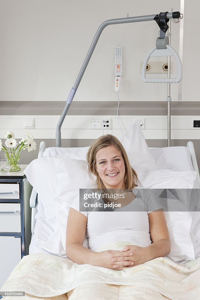 Lächelnden blonden Frau im Krankenhaus-Bett