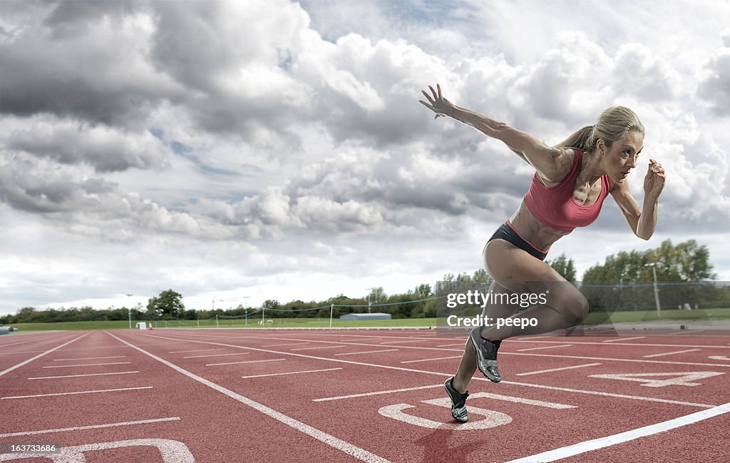 Mujer joven atleta tomando un descanso en una pista de atletismo