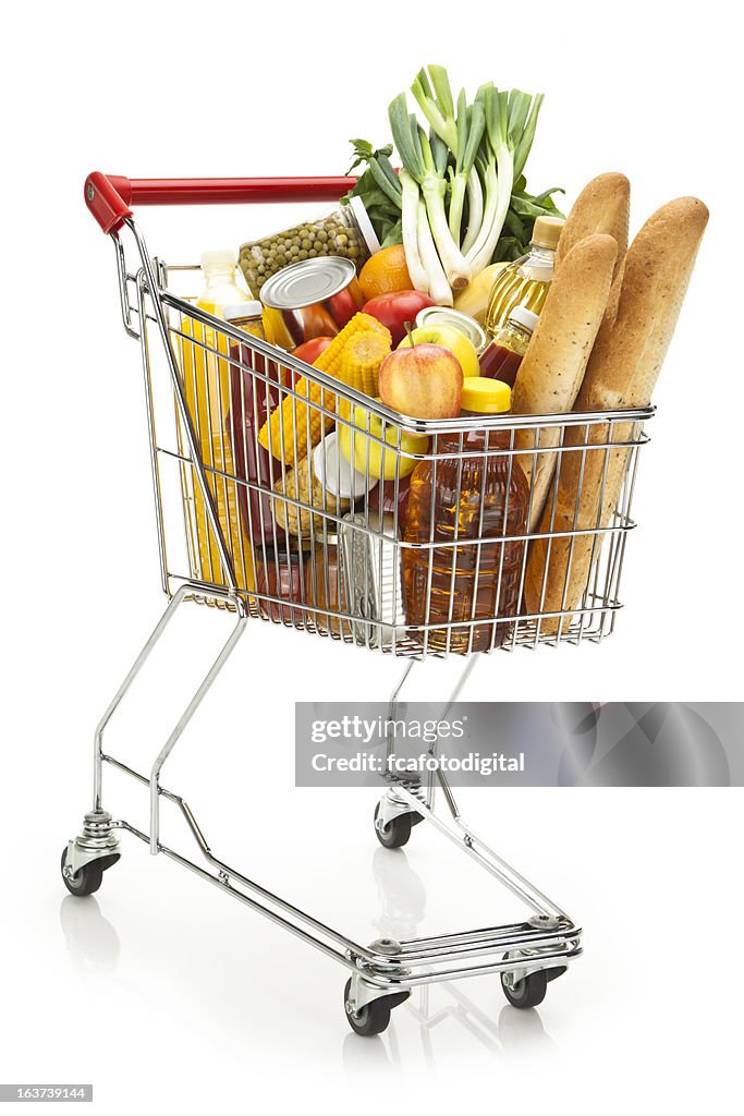 Shopping cart filled with variety of groceries on white backdrop