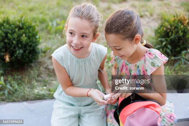 happy schoolgirls sharing candy on recess, back to school - children only stock pictures, royalty-free photos & images