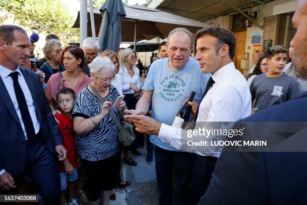 France's President Emmanuel Macron is offered a bottle of wine as he meets residents of Baumes-de-Venise, Southeastern France on September 1 during a...