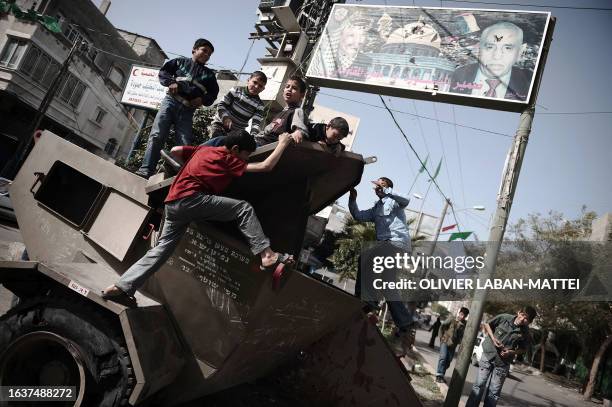 Palestinian boys play on an Israeli military trailer left behind by the army following its 22-days offensive in the Hamas-run territory on January...