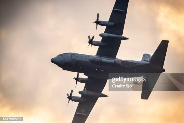 avión militar lockheed c-130 hércules volando en el aire durante la puesta del sol - hercules fotografías e imágenes de stock