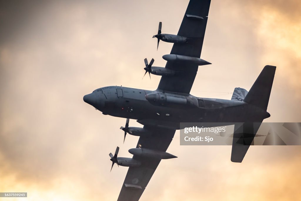 Lockheed C-130 Hercules military airplane flying in mid air during sunset