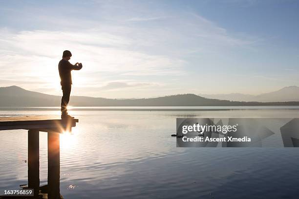 man takes picture of ducks swimming across lake - ducks stock pictures, royalty-free photos & images