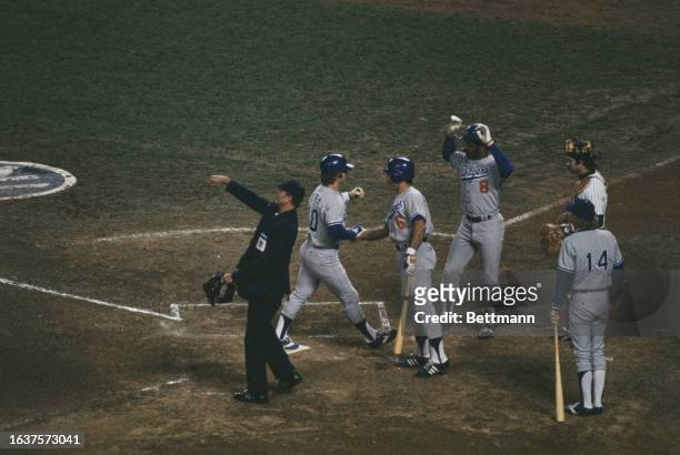 Umpire Ed Sudol throws the ball to pitcher Catfish Hunter as the Dodgers' Ron Cey crosses the plate in 1st, New York, October 12th 1977. Later, both...