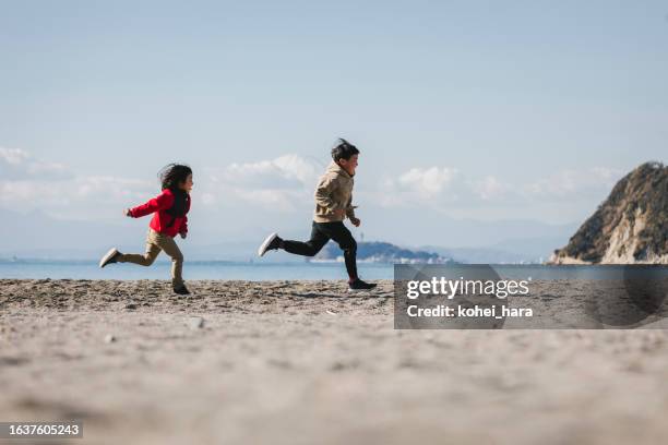 sibling running in the beach - zushi kanagawa stock pictures, royalty-free photos & images