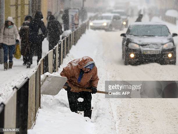 Communal service worker removes the snow from a road in Lviv on March 15, 2013. AFP PHOTO/ YURIY DYACHYSHYN